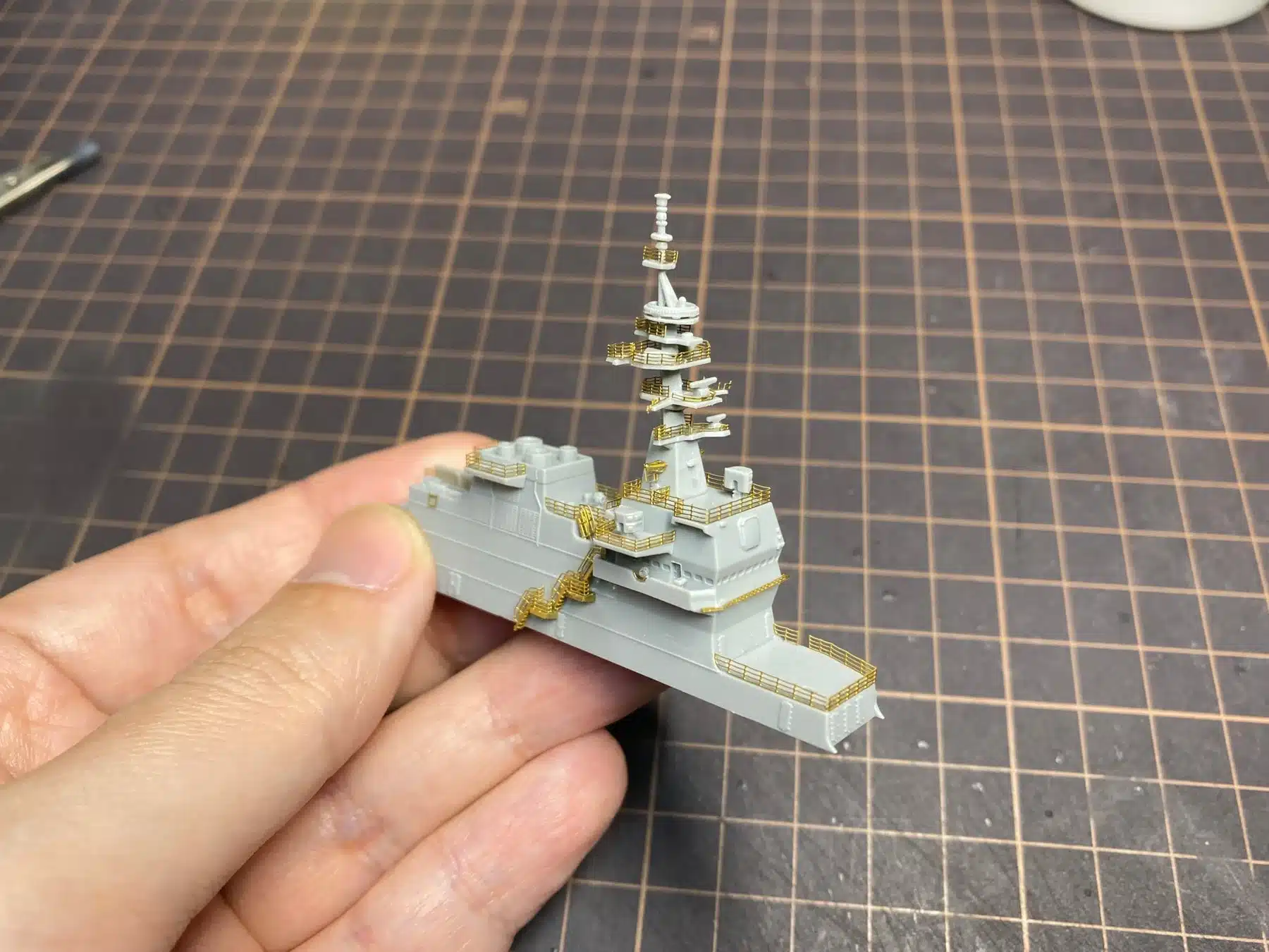 手が小型の艦船模型を持っている