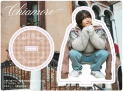 小林千晃のデビュー10周年記念写真集『Chiamore』のアクリルスタンドBの宣伝画像です。ヨーロッパ風の街並みを背景に、ニットとデニム姿の小林千晃がしゃがんでいます。